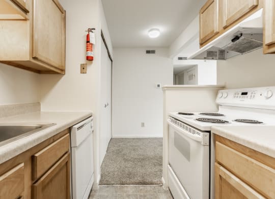 an empty kitchen with white appliances and wood cabinets at Polo Run Apartments, Indiana, 46142