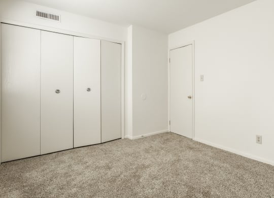 a bedroom with carpet and white walls and doors at Polo Run Apartments, Greenwood