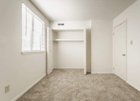 a bedroom with white walls and carpet and a closet at Polo Run Apartments, Greenwood