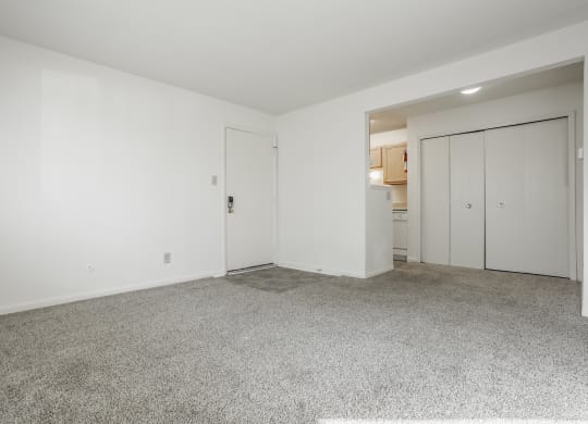 a living room with white walls and carpet and a door to a kitchen at Polo Run Apartments, Indiana, 46142