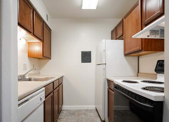 A small kitchen with a white refrigerator and a black stove top oven at Polo Run Apartments, Greenwood, 46142