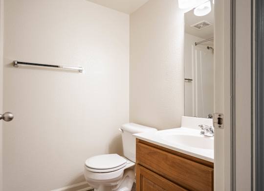 A white toilet sits next to a sink in a small bathroom at Polo Run Apartments, Greenwood, Indiana, 46142