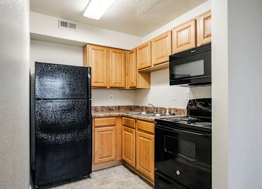 A kitchen with black appliances and wooden cabinets at Polo Run Apartments, Greenwood