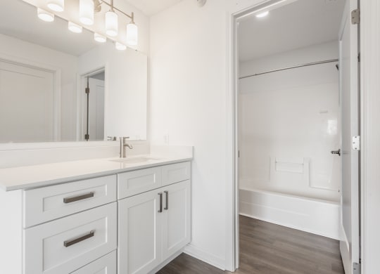 a white bathroom with a large mirror and a sink and a shower at Polo Run Apartments, Indiana, 46142