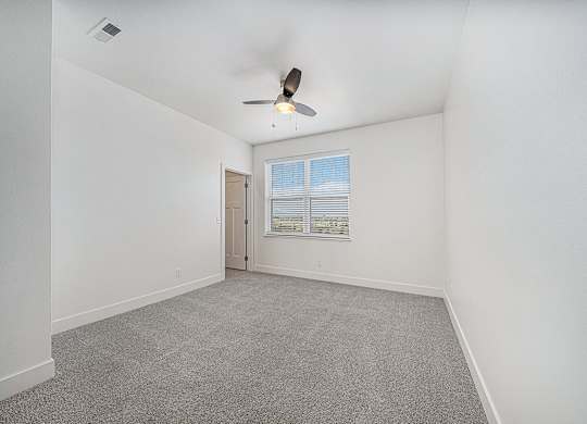 A bedroom with a ceiling fan, walk-in closet and carpeted floor at The Reserve at Destination Pointe, Iowa