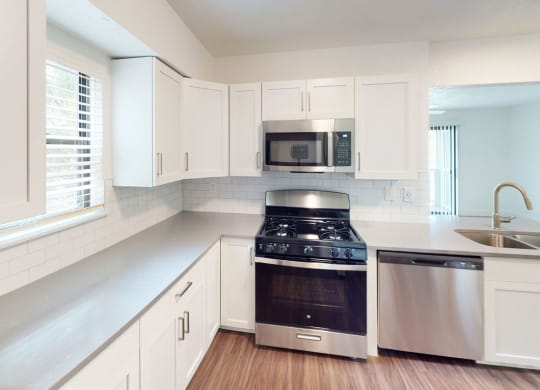a kitchen with white cabinets and a stove and a microwave at Green Ridge Apartments, Michigan, 49544