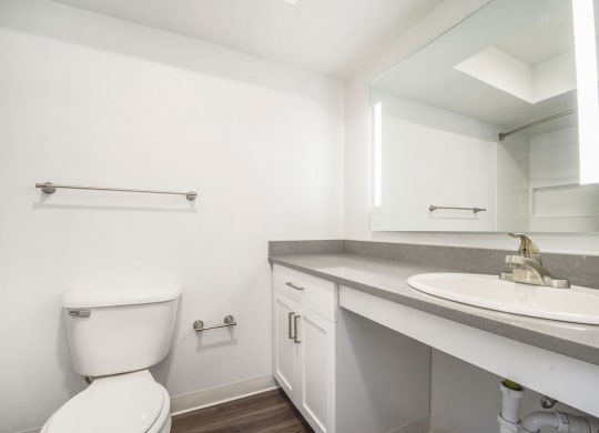 a bathroom with a toilet sink and mirror at Green Ridge Apartments, Grand Rapids, Michigan