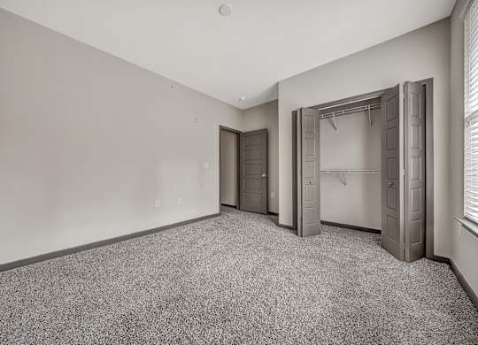 A room with grey carpet and three doors. at River Crossing Apartments, St. Charles, MO, 63303