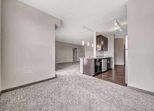 A spacious living room with a kitchen area in the background.at River Crossing Apartments, St. Charles, MO, 63303