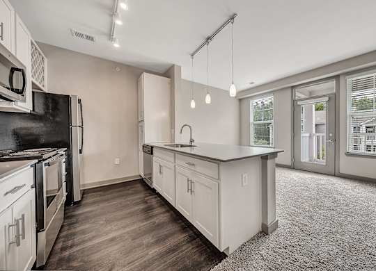 A kitchen with white cabinets and a black fridge. at River Crossing Apartments, St. Charles