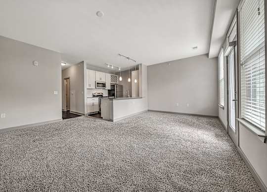 A spacious living room with a kitchen in the background.at River Crossing Apartments, St. Charles, MO