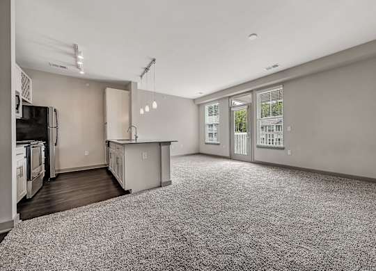 A spacious kitchen and living room with a grey carpet. at River Crossing Apartments, St. Charles, 63303