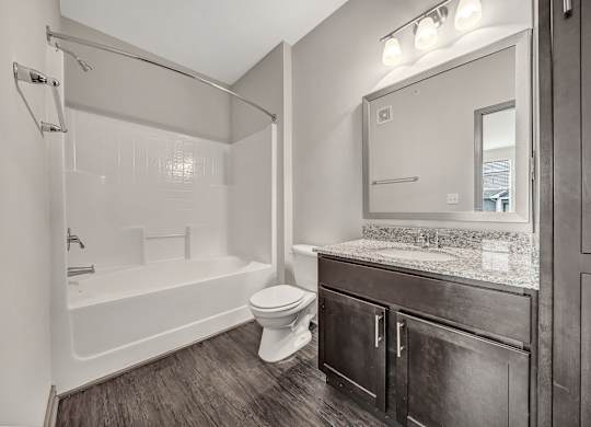 A bathroom with a white tub, toilet, and sink. at River Crossing Apartments, St. Charles, MO
