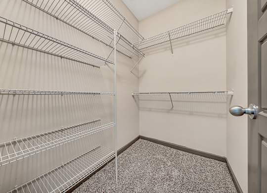 A walk-in closet with metal shelving and a carpeted floor. at River Crossing Apartments, St. Charles, Missouri