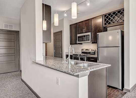 A kitchen with a granite countertop and stainless steel appliances. at River Crossing Apartments, St. Charles, MO