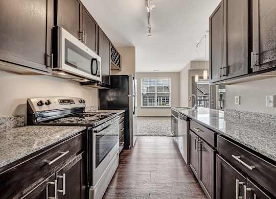 A modern kitchen with dark wood cabinets and granite countertops. at River Crossing Apartments, St. Charles, MO, 63303