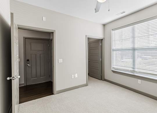 A room with a brown door, a window with blinds, and a white ceiling. at River Crossing Apartments, St. Charles, 63303