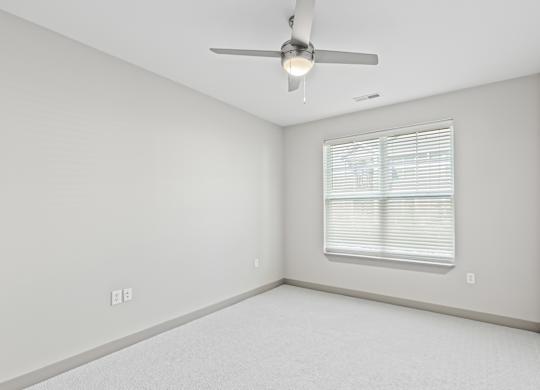 A room with a ceiling fan and a window with blinds.at River Crossing Apartments, Missouri