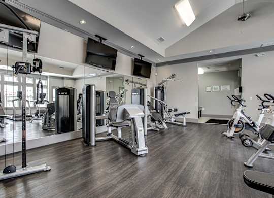 A spacious gym with a variety of equipment including treadmills, stationary bikes, and weight machines. at River Crossing Apartments, St. Charles, MO