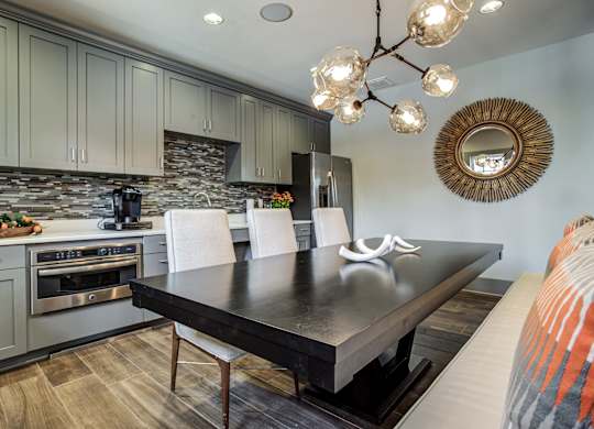 A modern kitchen with a black table and white chairs. at River Crossing Apartments, Missouri