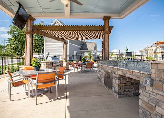 A patio with a stone fireplace and orange chairs. at River Crossing Apartments, St. Charles, MO