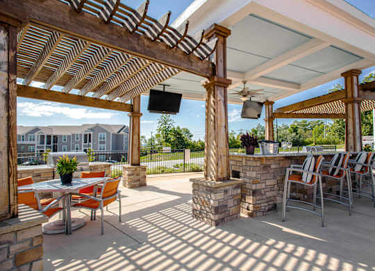 A patio with a table and chairs under a roof. at River Crossing Apartments, St. Charles