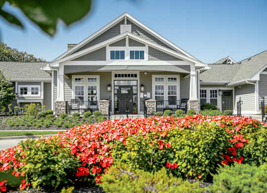 A house with a front yard of red flowers. at River Crossing Apartments, St. Charles, Missouri