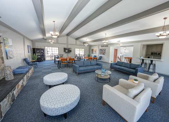 A spacious living room with a stone fireplace and a variety of seating options at Rivers Edge Apartments, Waterford, MI