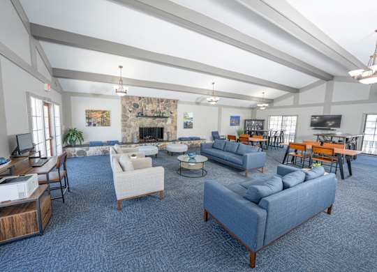 A spacious living room with a fireplace and a variety of seating options at Rivers Edge Apartments, Waterford, MI