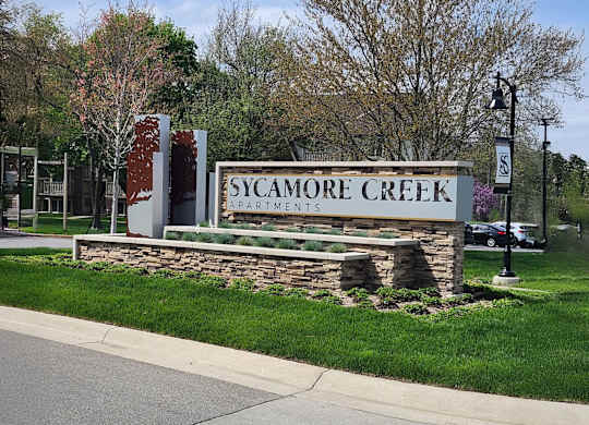Property Signage for Sycamore Creek Apartments is displayed in front of a grassy area.