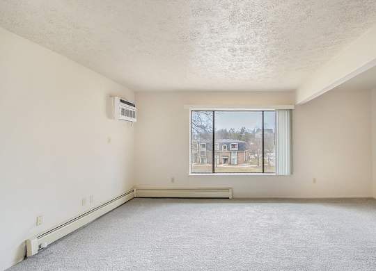 A living room with a large window overlooking a residential area at Seville Apartments, Kalamazoo, MI