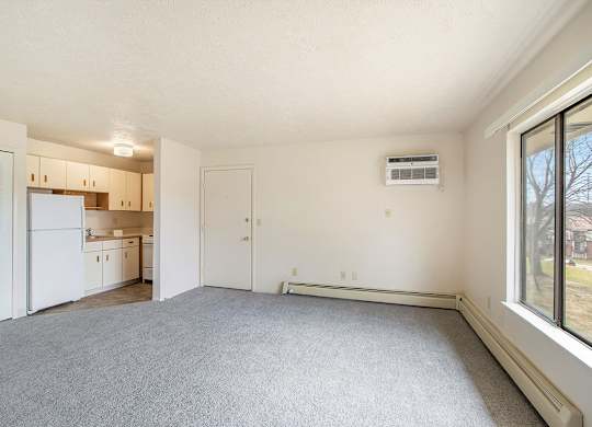 A spacious living room with a carpeted floor and a large window at Seville Apartments, Michigan