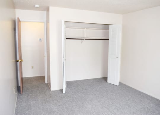 an empty bedroom with a closet and an open door at Seville Apartments in Kalamazoo, MI 49009