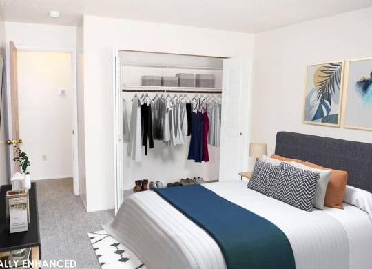 a bedroom with a bed and a closet full of clothes at Seville Apartments, Kalamazoo, MI, 49009