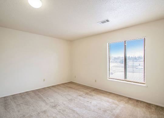 A bedroom with a carpeted floor and a window at Seville Apartments, Kalamazoo, MI
