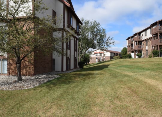 a large building with a grass lawn and trees at Seville Apartments, Michigan