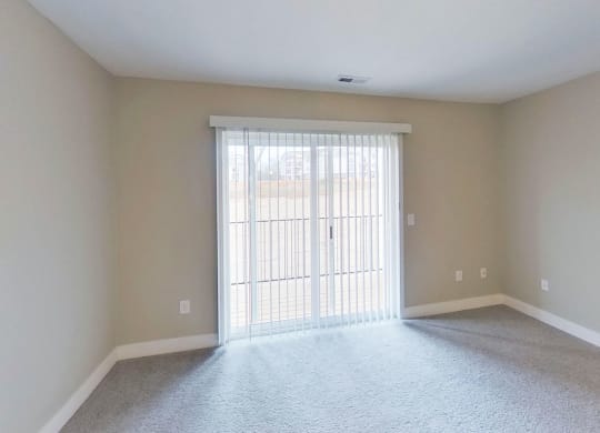 living room with a slider to a balcony end kitchen with a window at Signature Pointe Apartment Homes in Athens, AL