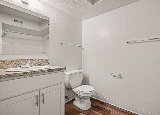 A white toilet sits in a bathroom next to a sink.