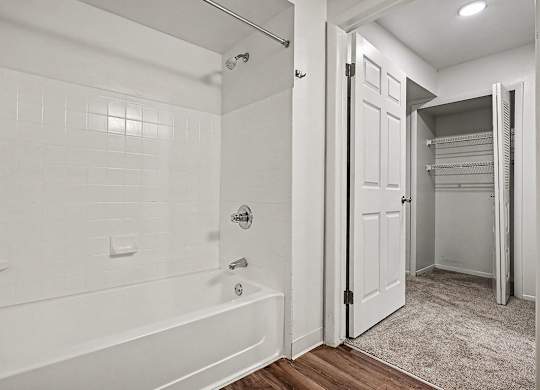 A white bathroom with a walk-in shower and a white door.