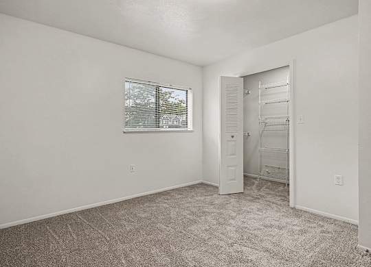 A room with a carpeted floor and a window with blinds.