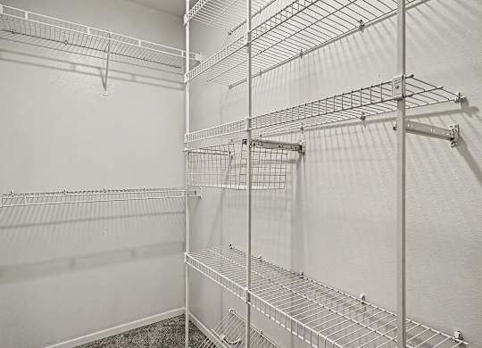 A white walk in closet with shelves and hooks.