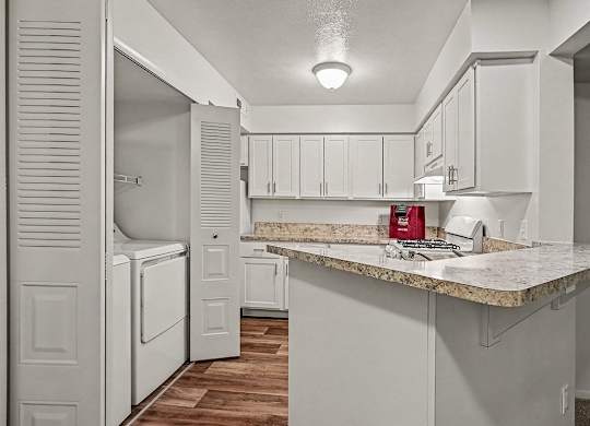 A kitchen with white cabinets and a marble countertop.