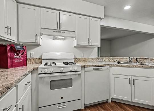 A kitchen with a white stove and cabinets.