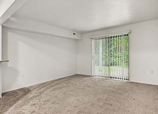 A room with a carpeted floor and a window with blinds.