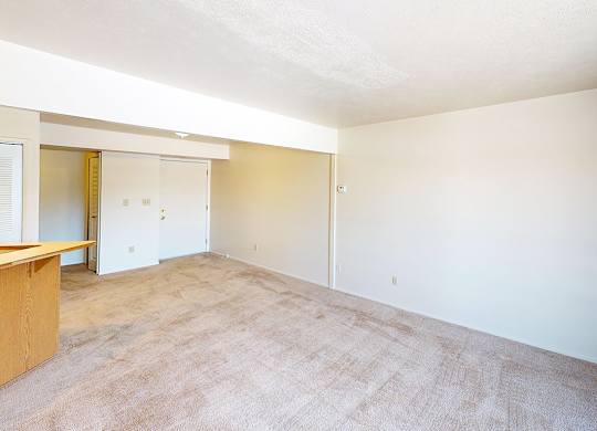 A living room with a carpeted floor and a kitchen with a breakfast bar at South Bridge Apartments in Fort Wayne, Indiana