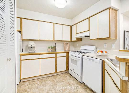 A kitchen with white appliances and wooden cabinets at South Bridge Apartments in Fort Wayne, IN