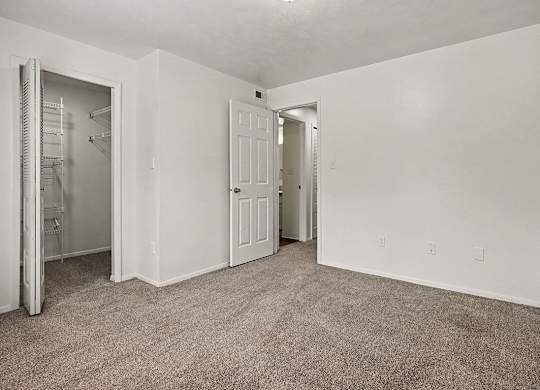 A room with a carpeted floor and two doors.