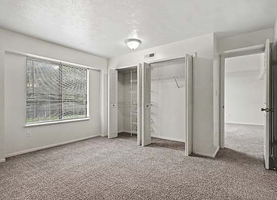A room with a carpeted floor and a window with blinds.