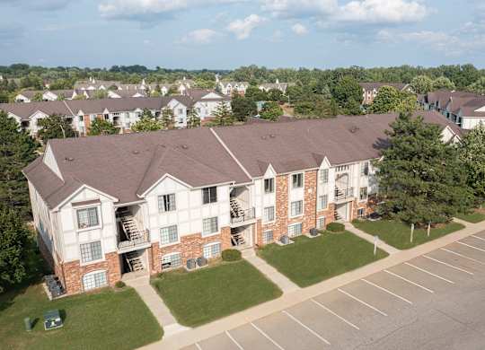 A large apartment complex with a parking lot in front.