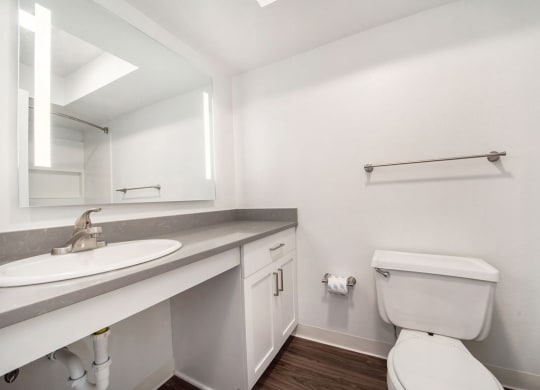 a bathroom with hard surface floors and a mirror at Stoney Pointe Apartment Homes, Wichita